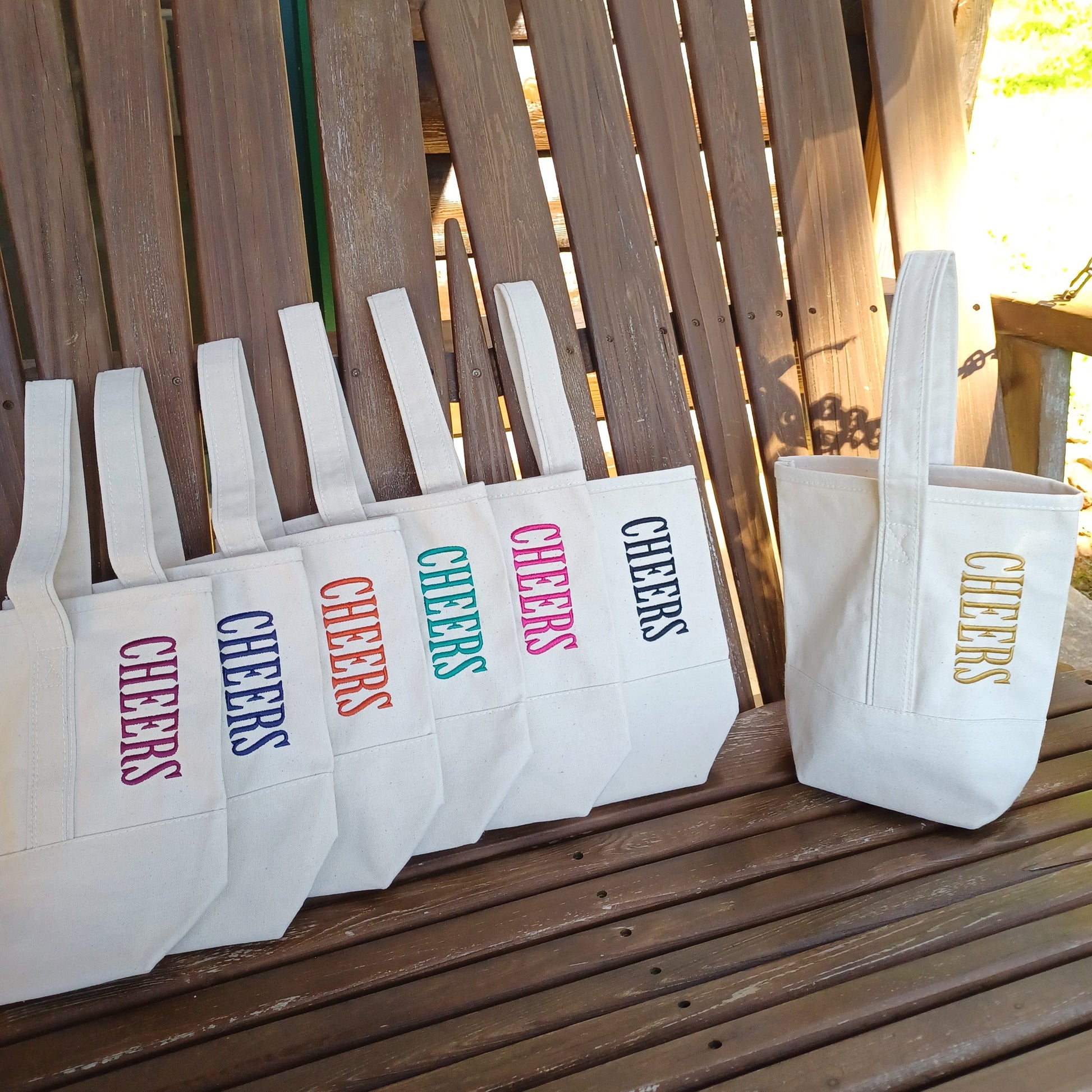natural canvas 2 bottle wine totes with the word CHEERS embroidered in different thread colors