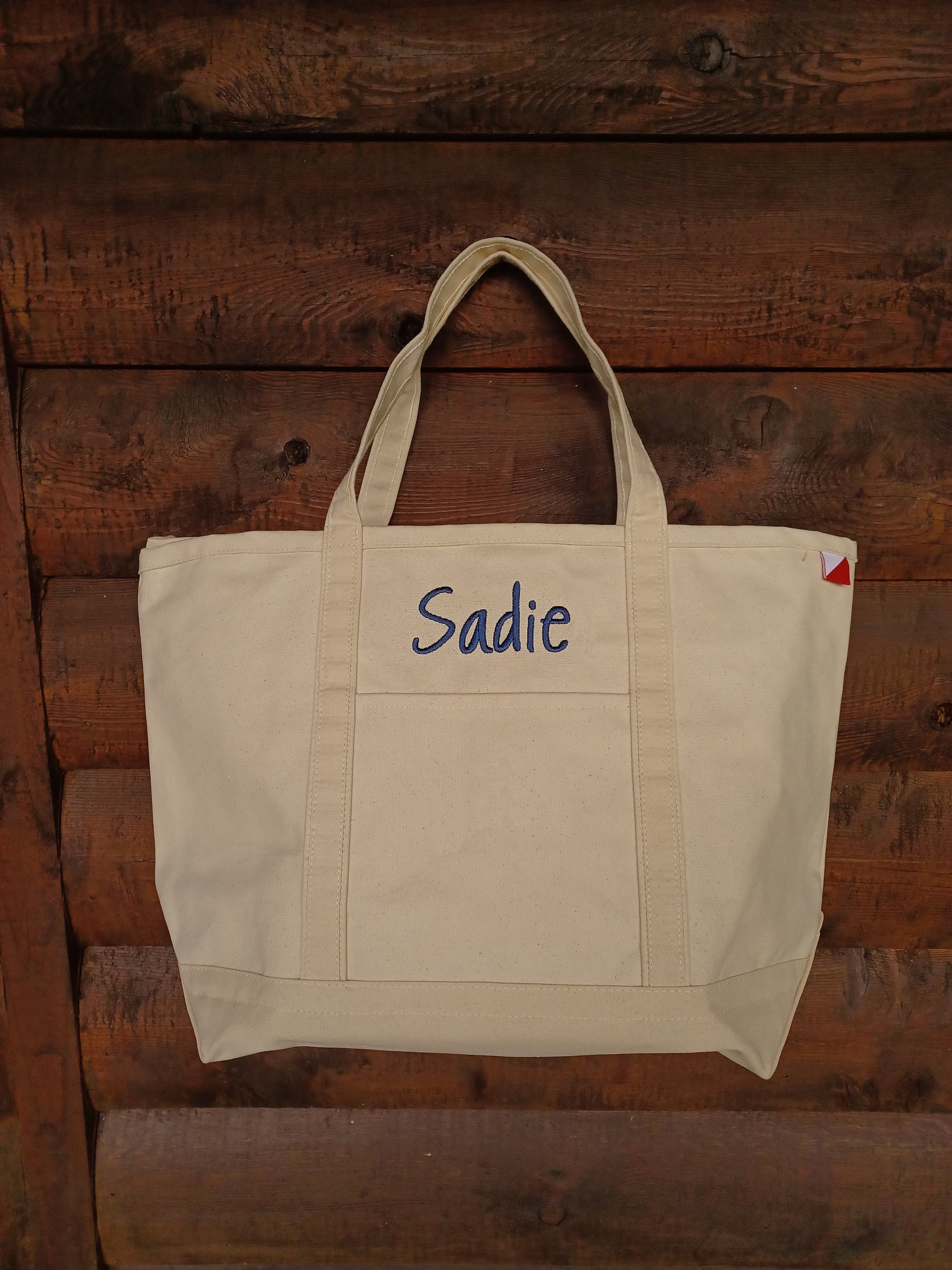 natural colored canvas tote with embroidered name above front pocket
