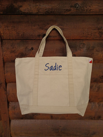 natural colored canvas tote with embroidered name above front pocket