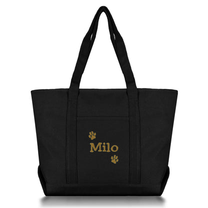 Black tote bag with dog name and paws embroidered on it against a white background