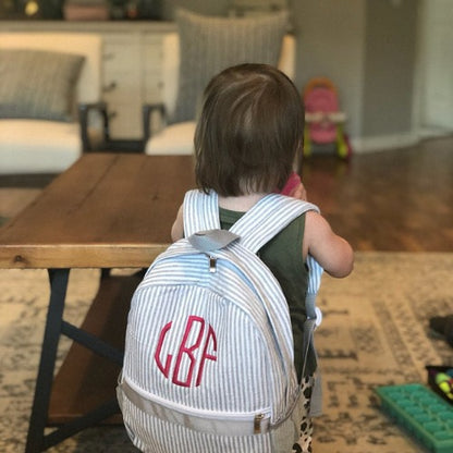 gray seersucker toddler backpack with a monogram,  being worn by a toddler