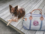 best dog in the world laying next to our gray striped canvas weekender bag with crimson round monogram with leather handles